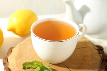 Aromatic tea in cup, lemon, mint and teapot on table, closeup