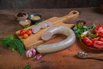 Meat delicacies on a wooden table in the kitchen among greens and vegetables