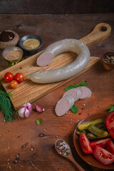 Meat delicacies on a wooden table in the kitchen among greens and vegetables