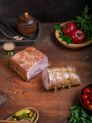 Meat delicacies on a wooden table in the kitchen among greens and vegetables