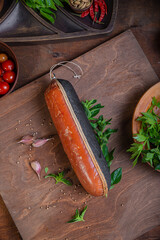 Meat delicacies on a wooden table in the kitchen among greens and vegetables
