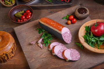 Meat delicacies on a wooden table in the kitchen among greens and vegetables