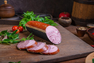 Meat delicacies on a wooden table in the kitchen among greens and vegetables