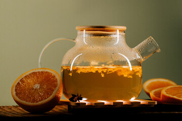Freshly brewed green tea with orange slices on a wooden surface in a cozy setting