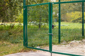 Metal mesh gate with lock and chain on green area horizontal photo