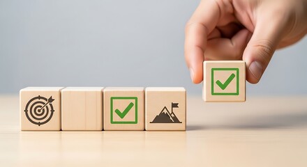Hand placing wooden block with check mark symbol representing achievement of business goals and objectives.