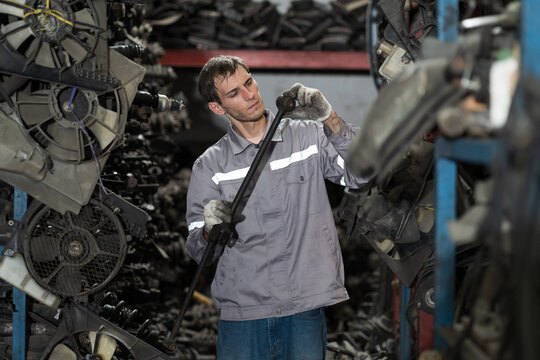 Automotive spare parts warehouse. Male warehouse worker inspecting spare parts in auto parts warehouse. Male mechanic worker checking spare parts in workplace - Powered by Adobe