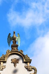 Fototapeta premium Ornate Architectural Detail with Winged Creature Sculpture Against Blue Sky