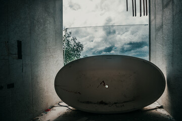 A room in an abandoned hotel. A white bathtub on the floor. A view of palm trees from the abandoned...