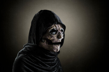 Creepy figure in hooded cloak over dark misty background at night