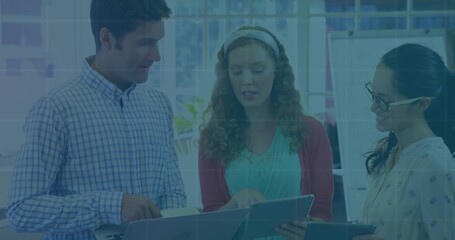 Collaborating trio examining two touchscreen tablets in office with whiteboard and plant