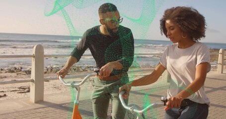 Walking side by side, friends holding bicycles on seaside promenade by railing and posts, chatting