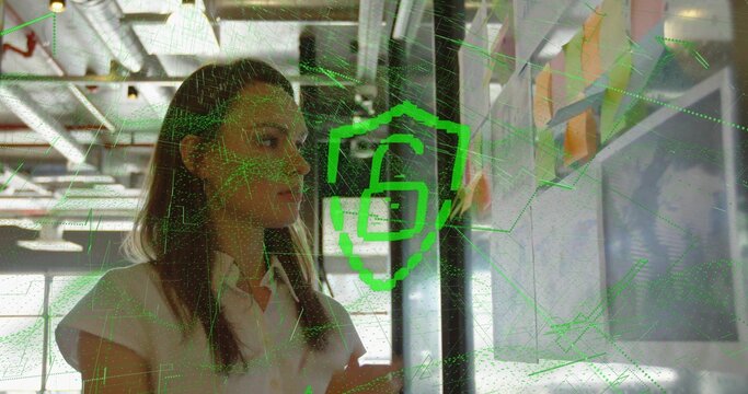 Arranging woman reviewing colorful sticky notes on whiteboard in office with padlock grid overlay - Powered by Adobe