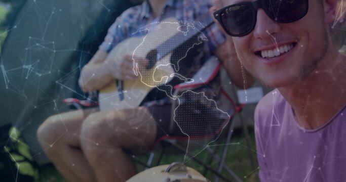 Smiling man wearing sunglasses, purple tee sitting at campsite with guitar and grill, copy space - Powered by Adobe