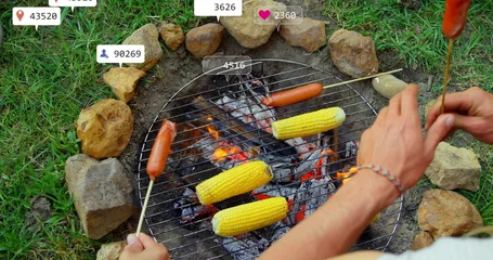 Gardinen Grillabend Friends roasting corn and hot dog skewers over backyard fire pit, with grill grate, glowing coals  © vectorfusionart
