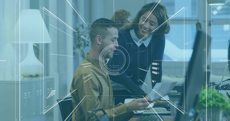 Reviewing printed report coworkers in business casual attire at office desk, with monitor and plant