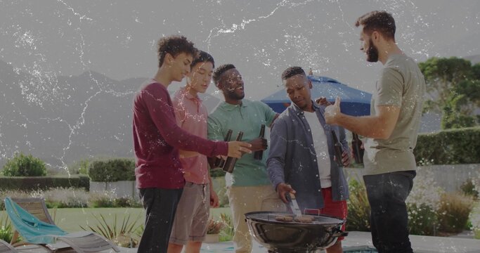 Grilling group of five friends turning meats on charcoal grill at poolside patio, with summer wear