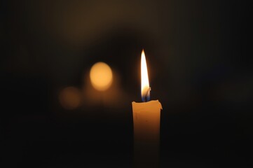 Fototapeta premium Close-Up of a Glowing Candle Flame Casting a Warm and Ethereal Light in the Darkness