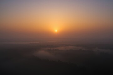 Obraz premium Serene Sunrise Over Misty Forest Landscape Painting with Warm Hues and Peaceful Ambiance