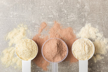 Protein powder. A spoonful of protein powder on a table. Different flavors of whey protein powder. Sports nutrition concept. Gym. Amino acid food supplement, creatine powder. Copy space.