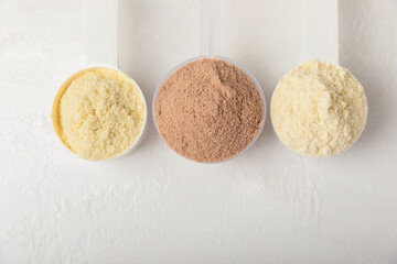 Protein powder. A spoonful of protein powder on a table. Different flavors of whey protein powder. Sports nutrition concept. Gym. Amino acid food supplement, creatine powder. Copy space.