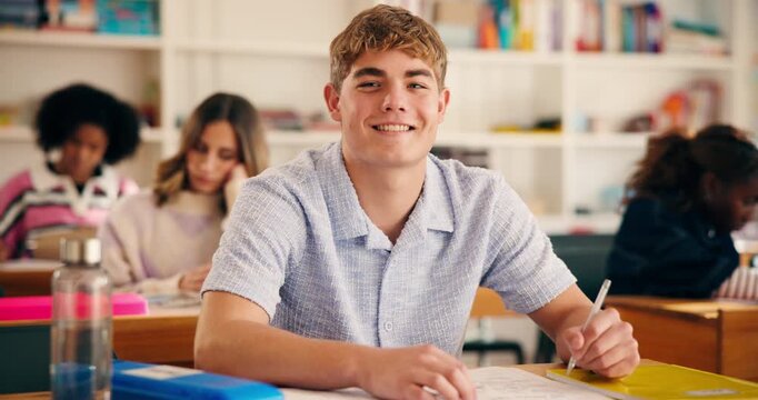 Smile, face and student in high school with writing test, exam or assessment for education. Happy, learning and portrait of boy teenager with books for notes for studying in classroom at campus.