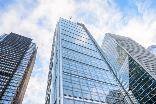 Low angle view of glass office skyscrapers against blue sky with clouds on a winter morning