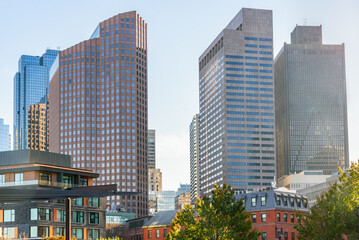 High rise office buildings in downtown Boston at sunset in autumn. Modern and tradtional apartment buildings are visible in foreground. Lens flare.