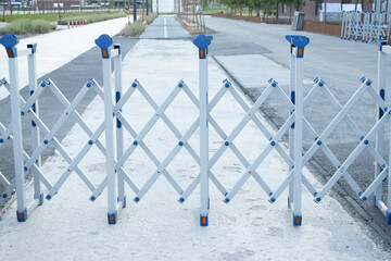 Accordion barrier spans across pavement to block a lane. Practical solution for temporary closure,...