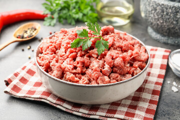 Raw minced meat with parsley and spices on grey table, closeup