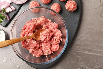 Raw meatballs, ground meat and onion slices on grey table, flat lay