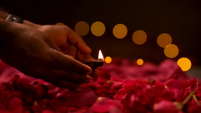 Close up of hand placing glowing Diya lamp on floor during Diwali festival