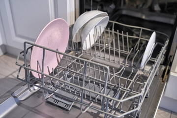 Open dishwasher with clean dishes inside kitchen appliance for efficient home cleaning.