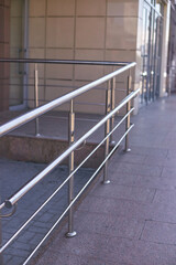 Stainless steel handrail on modern urban building exterior for accessibility and safety.