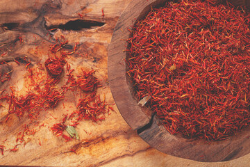 Spice saffron threads, in a wooden bowl, on a wooden table, top view, close-up,