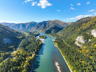 Fototapeta premium Expansive aerial panorama of the wide, turquoise Katun River flowing between two heavily forested mountain ranges in a sunny, clear day