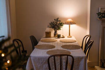 Warmly lit festive dinner table with rustic decor, Christmas decorations, candles, and a cozy winter atmosphere.	