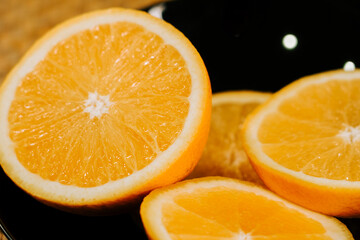 Freshly cut orange slices on a black plate in a bright kitchen setting