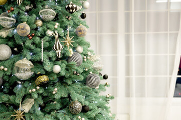 Christmas Tree Decorated with Silver, Gold, and Black Ornaments Next to a Window