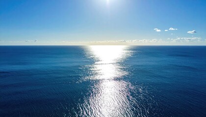 Obraz premium Aerial view of a vast, shimmering ocean under a bright, sunny, blue sky