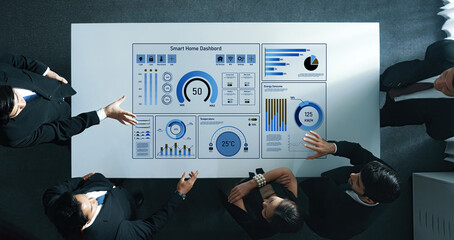 A business team engages in detailed analysis of a smart home dashboard displaying key data for energy management and decision-making processes within a contemporary office environment. Trope
