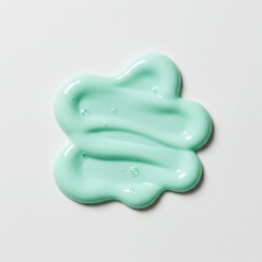 A dollop of creamy light green cosmetic product or toothpaste swirled on a white background