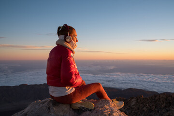 Woman relaxing at teide volcano sunrise with music