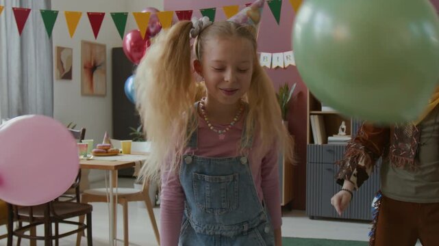 Group of happy children celebrating birthday in decorated party room with colorful balloons and banners
