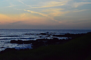 Fototapeta premium Twilight over the Atlantic Ocean near Santa María de Oia, Galicia, Spain, with soft waves, rocky shore, and colorful skies blending into the serene horizon 