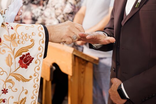 Orthodox Wedding Ceremony: Priest Blessing Rings with Embroidered Vestment, Golden Lighting, Religious Tradition, Intimate Chapel Interior