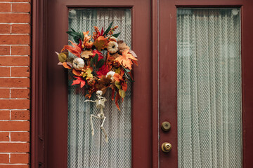 Colorful autumn wreath decorates front door while skeleton adds a spooky touch for Halloween season