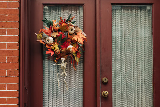 Colorful autumn wreath decorates front door while skeleton adds a spooky touch for Halloween season