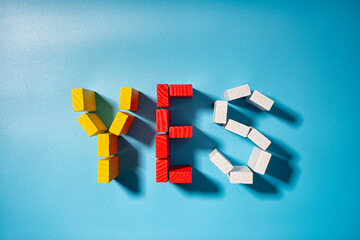 Colorful blocks arranged to spell yes in bold letters on a bright blue background showcasing creativity and positivity in playful art