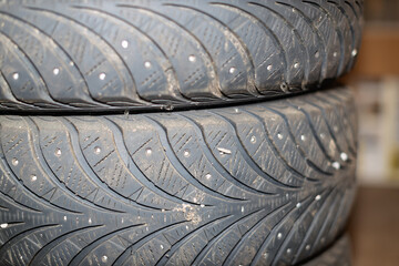 A close-up view reveals the detailed tread pattern and metal studs on two stacked, used winter...